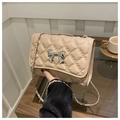 Primer plano de bolso bandolera acolchado beige con lazo metálico plateado y cadena - Caqui