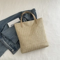 Minimalistische Strohtasche in Beige mit braunen Ledergriffen auf Denim-Hintergrund - Khaki