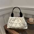 Borsa tote trapuntata bianca con manici neri su un tavolo di legno in ambiente accogliente - Bianco