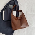 Brown geometric patchwork shoulder bag displayed on a navy blazer for daily commute - Brown