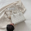 White quilted handbag with gold stitching and crossbody strap on cream suit - White