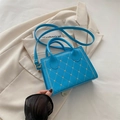 Sky blue quilted PU leather handbag with gold heart studs on cream blazer background - Blue