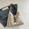 Beigefarbene Tragetasche mit Blattmuster und braunem Lederriemen auf blauem Denim - Khaki