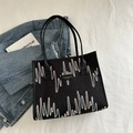 Black quilted tote bag featuring colorful wave embroidery and sleek top handles - Black