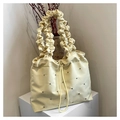 Dettaglio della borsa tote beige con manico a pieghe e decorazioni di rivetti argento - Giallo