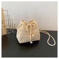 Detail of beige straw bucket bag with woven texture, drawstring closure, and tassel beads - Off White