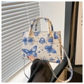 Detail der kleinen Handtasche mit blauem Schmetterlings- und Sternbildmuster auf Weiß - Blau