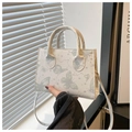 Detailansicht der weißen Handtasche mit grünen Schmetterlingsmustern und Umhängeriemen - Grün