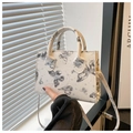 Detail einer weißen Mini-Handtasche mit schwarzen Schmetterlingsmustern und Sternen - Grau