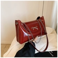 Detail of burgundy glossy leather tote with silver bow and chain strap on white blazer - Red