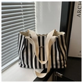 Detalle de bolso tote de lona a rayas con placa de metal en el alféizar de ventana - Negro
