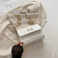Weiße Umhängetasche aus Leder mit goldener Schleifenschließe und eleganter Kette - Weiß