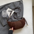 Dunkelbraune Wildleder-Croissant-Tasche mit Nähten und Schultergurt auf weißem Laken - Hellkaffee