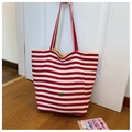 Detail der rot-weiß gestreiften Canvas-Tasche mit dem ovalen Handmade-Logo-Aufnäher - Rot