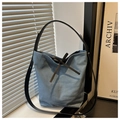 Detail der hellblauen Denim-Beuteltasche mit schwarzer Lederschleife und breitem Gurt - Hellblau