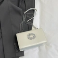 Elegant cream chain square bag with rhinestone buckle on a gray blazer background - White
