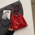Détail du sac seau rouge brillant avec cordon noir et boucle papillon en métal - Bordeaux