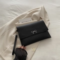 Minimalist black envelope clutch bag featuring a silver metal bow accent and wrist strap - Black