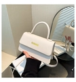 Detailansicht der beigefarbenen Ledertasche mit Lychee-Struktur und gelbem FASHION-Text - Weiß