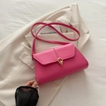 Borsa a tracolla rosa acceso in pelle con chiusura dorata su un blazer bianco - rosa acceso