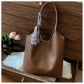 Detail of dark brown pebble leather tote bag with silk scarf on handle and fashion tag - Coffee