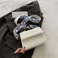 White quilted crossbody bag with blue patterned wide strap and gold hardware on blazer - White