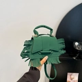 Green suede handbag with fringe tassels and gold hardware shown in hand display - Green