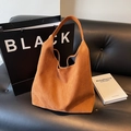 Bolso tote de cuero mate marrón con diseño minimalista Hobo sobre un sofá de cuero - Marrón