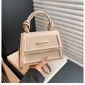 Detalle de bolso beige que muestra la textura de cuero mate y asa con diseño de nudo - Caqui