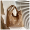 Detail of khaki corduroy tote bag showing white letter embroidery and soft ribbed texture - Khaki