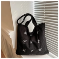 Detail of black corduroy tote bag showing textured fabric and white art embroidery - Black