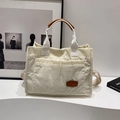 Off-white corduroy tote bag with brown leather accents and adjustable strap in lifestyle setting - No Pendant / Brown
