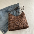 Elegante borsa tote leopardata con tracolla in pelle marrone su sfondo denim - Marrone