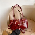 Deep red patent leather bowling bag with gold zippers and embossed Fashion text on a chair - Red