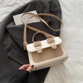 Bolso bandolera beige y caqui con solapa y tachuelas doradas sobre un traje - Caqui