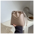 Detail der Tunnelzug-Beuteltasche mit matter beige Textur und eleganten geschwungenen Taschen - Khaki