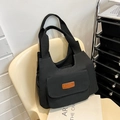 Large capacity black canvas tote bag with front pocket and fashion label on a chair - Black