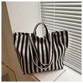 Close-up of black and white striped canvas tote bag on books with soft natural lighting - Black