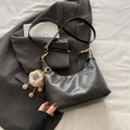 Black leather hobo bag with adjustable strap and brown plush toy charm on blazer background - Black (With Ornament)