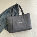 Bolso tote de pana gris con etiqueta Fashion Instinct sobre fondo de mezclilla azul - Gris