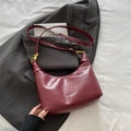 Chic wine red leather hobo bag with adjustable strap shown against a grey blazer backdrop - Red (No Charm)