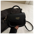 Detail of a black leather saddle bag with gold logo on a minimalist background - Black