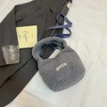 Sac seau gris en laine bouclée avec bandoulière bleue et étiquette logo sur lit blanc - Sans pendentif / Bleu Brume