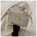 Close-up of quilted cream faux leather crossbody bag with golden bow buckle detail - White