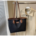 Detailaufnahme einer schwarzen Oxford-Tasche mit braunen Ledergriffen und Aufnäher - Schwarz und Braun