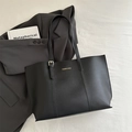 Minimalistische schwarze Tote Bag mit goldener Schrift auf grauem Blazer-Hintergrund - Schwarz