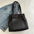 Borsa tote nera in nylon con tasca in pelle e tracolla presentata su tessuto bianco - Nero