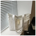 Detail of white nylon tote bag with side pockets and rope detail near a laptop - White