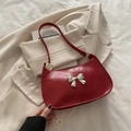 Red glossy patent leather crescent shoulder bag with metallic bow charm and top handle - Red
