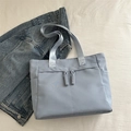 Light blue-grey nylon tote bag with rope knot details on beige fabric background - Blue